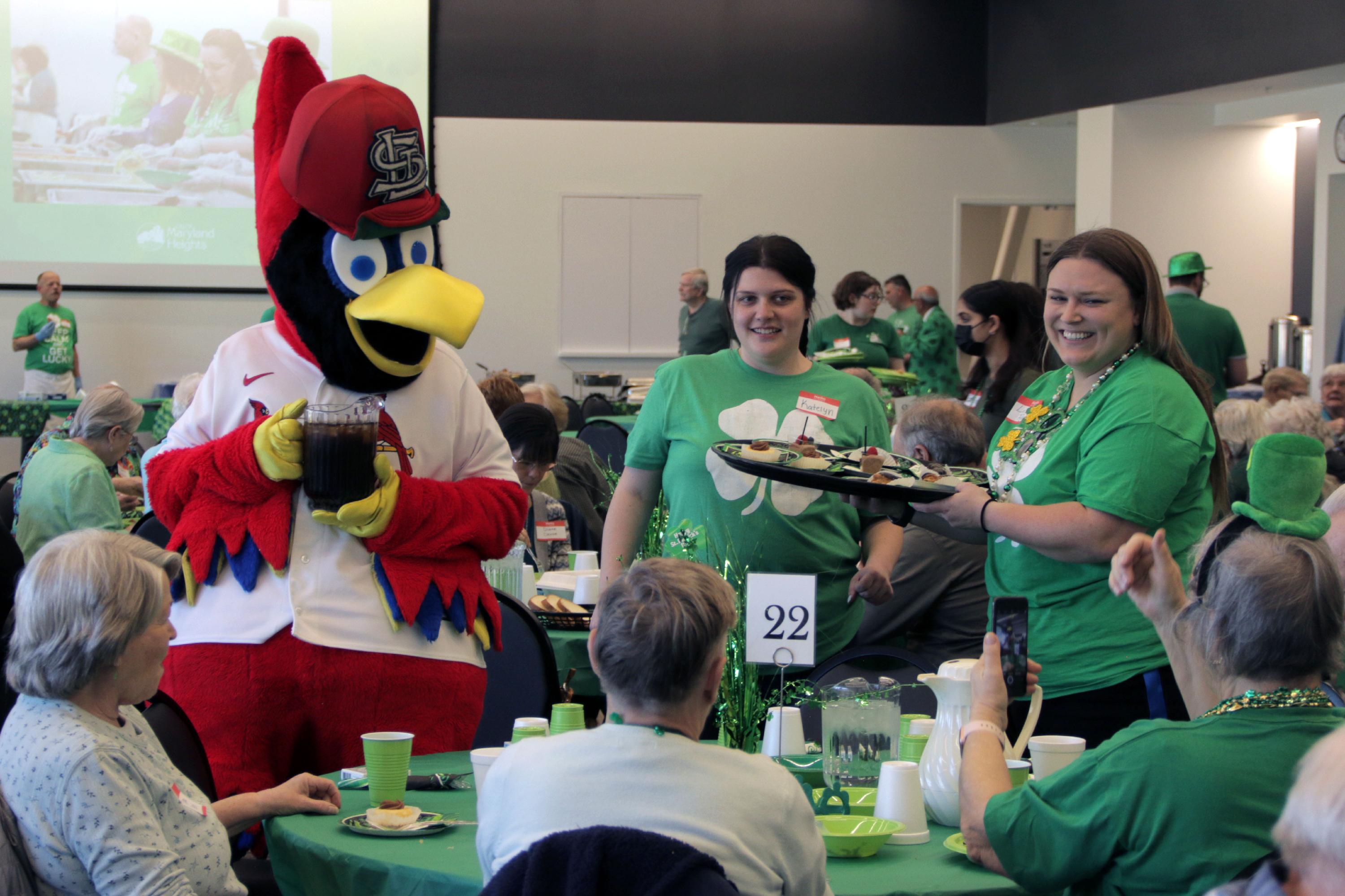 mascot and employees serving food to senior citizens